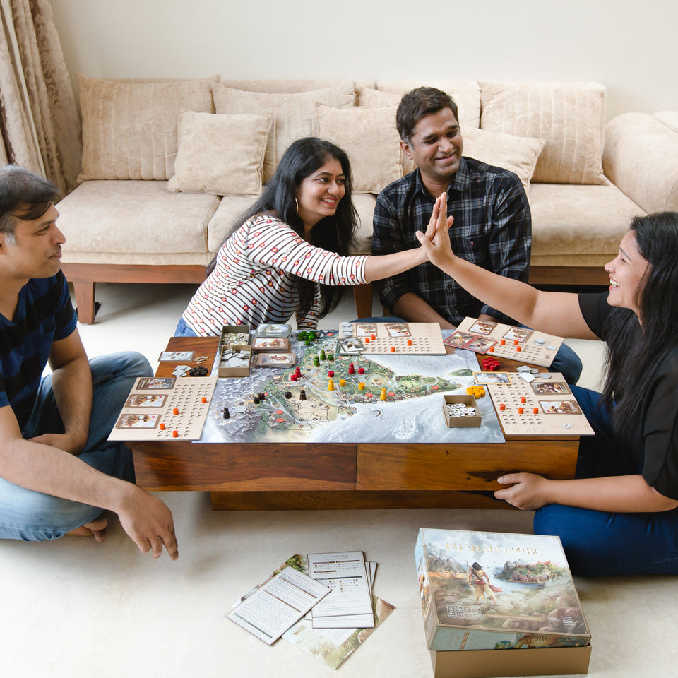 Two young women high five while playing a GoIndia Games board game together with their families